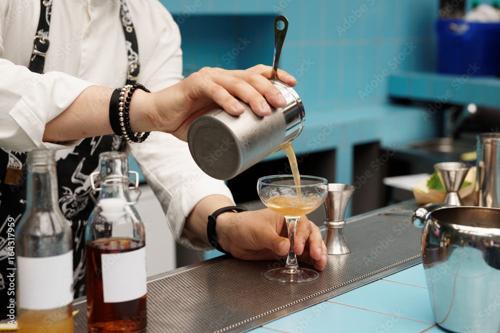 Bartender is pouring cocktail from shaker