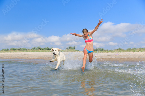 happy girl playing with a dog on the beach