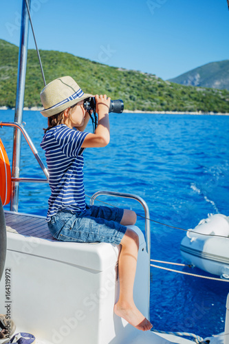 Little boy captain on board of sailing yacht on summer cruise. Travel adventure, yachting with child on family vacation. © Max Topchii