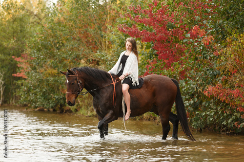 Hübsche Reiterin mit Pferd im See