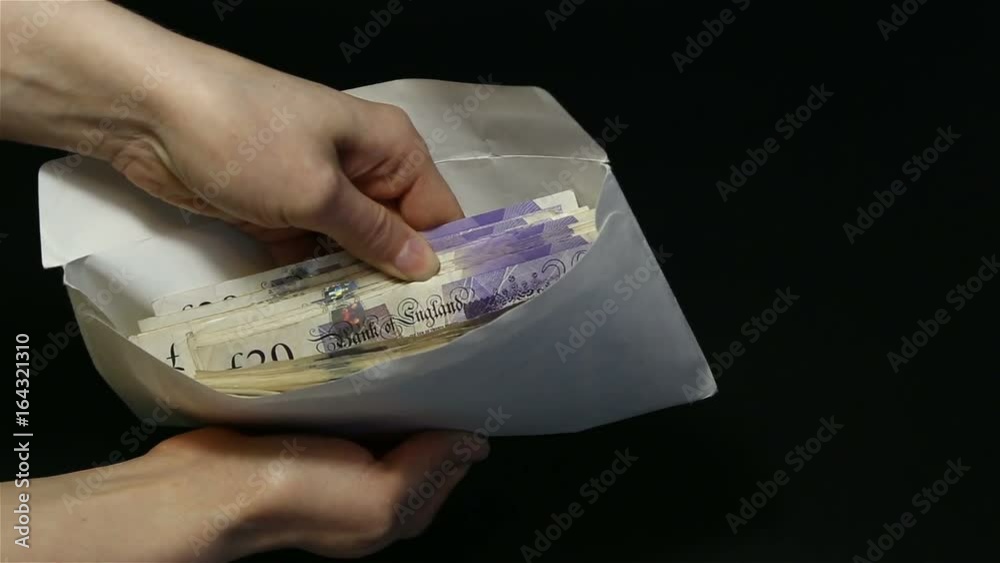 Close-up man's hand giving envelope with money to woman's hand. Black background. The transfer of cash from hand to hand. Female hands open an envelope and counting a lot of 20 pounds (GBP) banknotes.