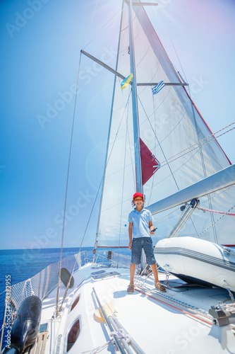 Little boy captain on board of sailing yacht on summer cruise. Travel adventure, yachting with child on family vacation. © Max Topchii