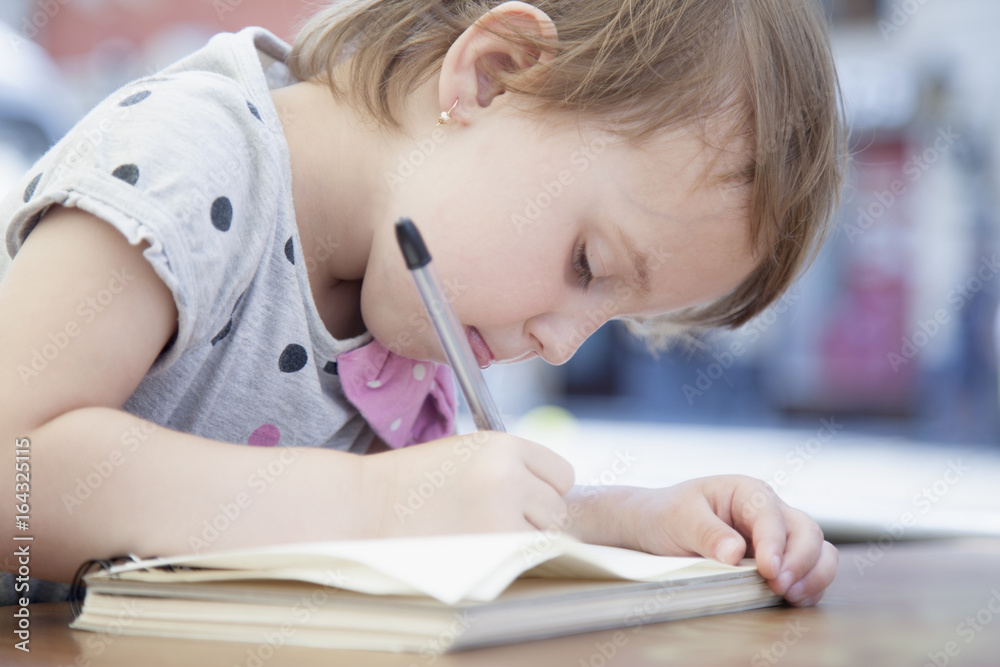 Little beautiful girl writing in her book (Education, knowledge, work, success concept) Little beautiful girl writing in her book (Education, knowledge, work, success concept)