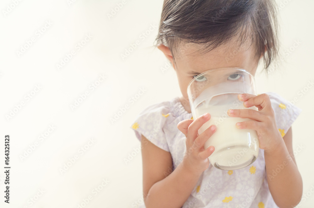 Cute asian toddler girl drinking milk from big glass on white background. Cute asian toddler girl drinking milk from big glass on white background.