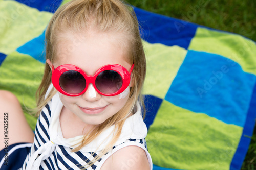 adorable school age girl with sunscreen and sunglasses on outside in summertime