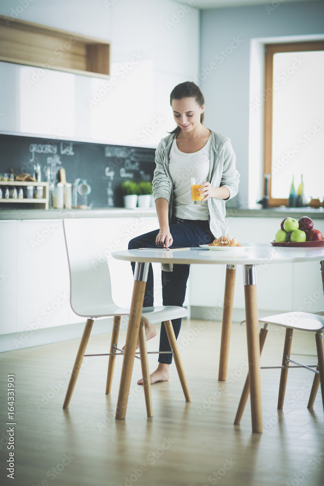 Young woman with orange juice and tablet in kitchen. Young woman with orange juice and tablet in kitchen.