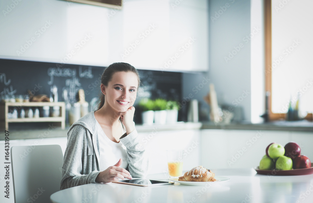 Young woman with orange juice and tablet in kitchen. Young woman with orange juice and tablet in kitchen.