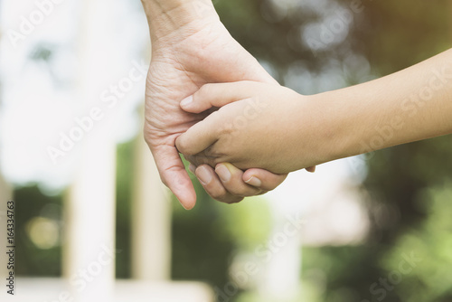 Mother holding a hand of his son in summer day