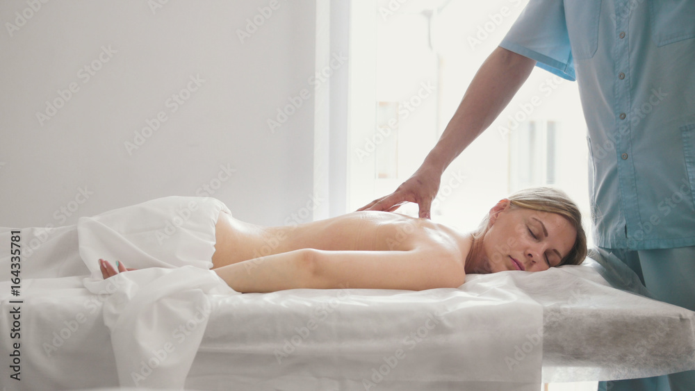 Young woman lies on a massage table - therapeutic manual therapy