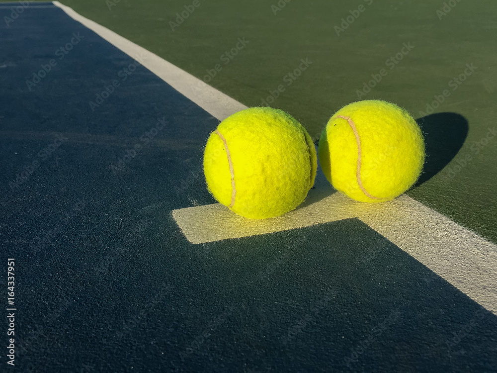 Two Bright Yellow Tennis Balls on the Tennis Court with Green and Blue Colours