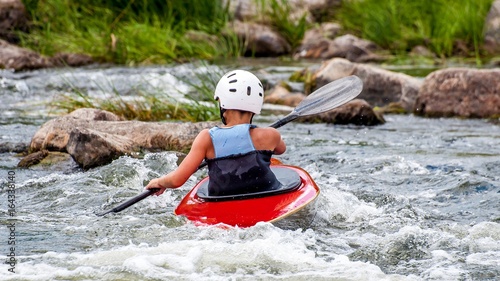 Fototapeta Naklejka Na Ścianę i Meble -  A teenager trains in the art of kayaking. Slalom boats on rough river rapids. The child is skillfully engaged in rafting.