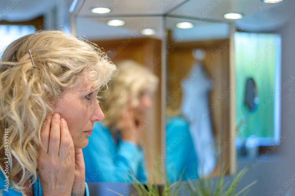 Middle-aged woman looking at herself in a mirror Middle-aged woman looking at herself in a mirror