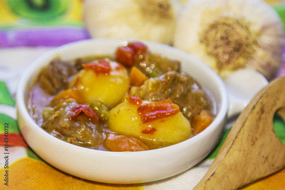 Ceramic casserole with meat stew on colorful tablecloth Ceramic casserole with meat stew on colorful tablecloth