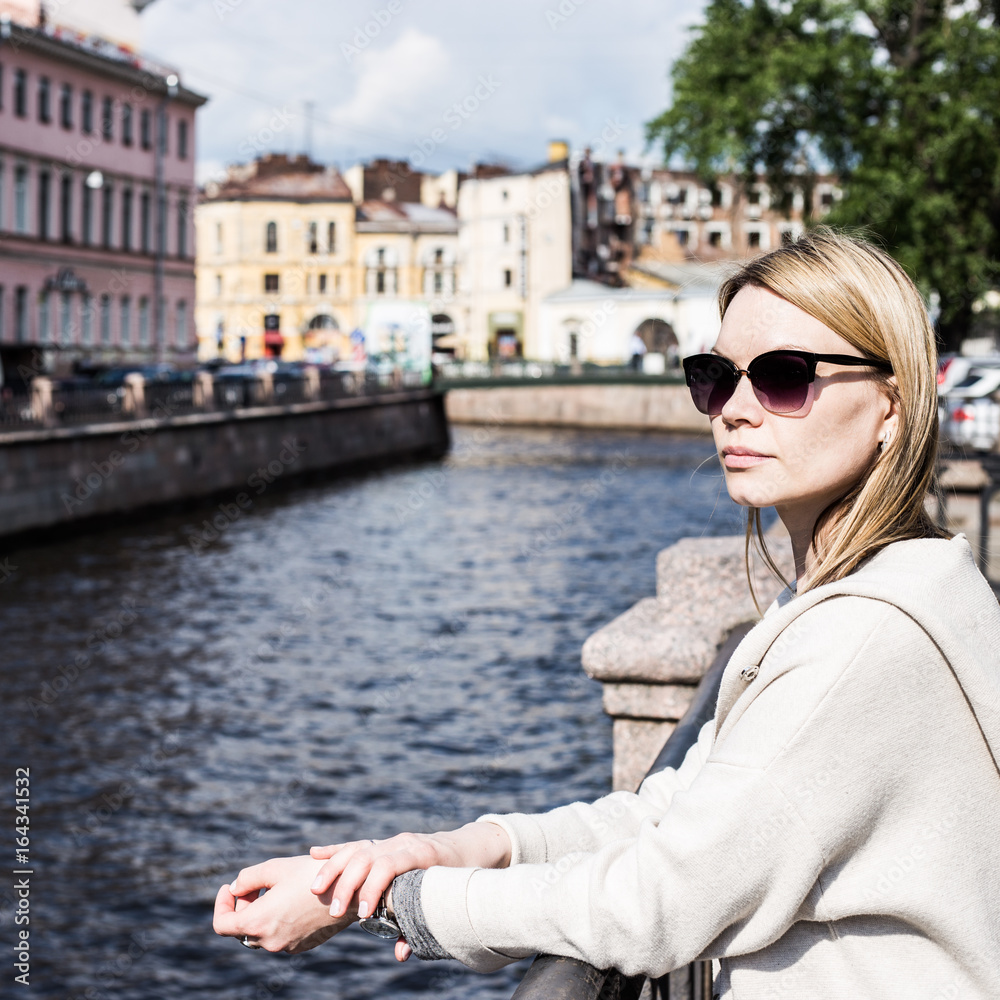 Shot of a beautiful woman standing a small bridge over the canal while on sightseeing in a foreign city