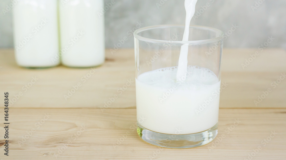man pouring a milk on a wooden table. man pouring a milk on a wooden table.
