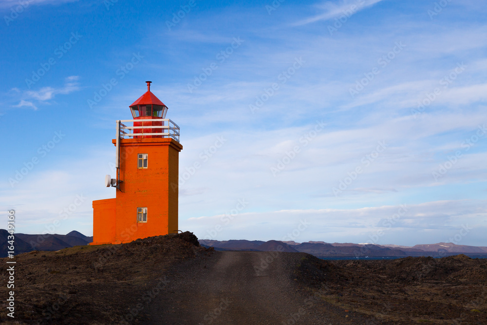 Orange lighthouse on a stony coast in Iceland
