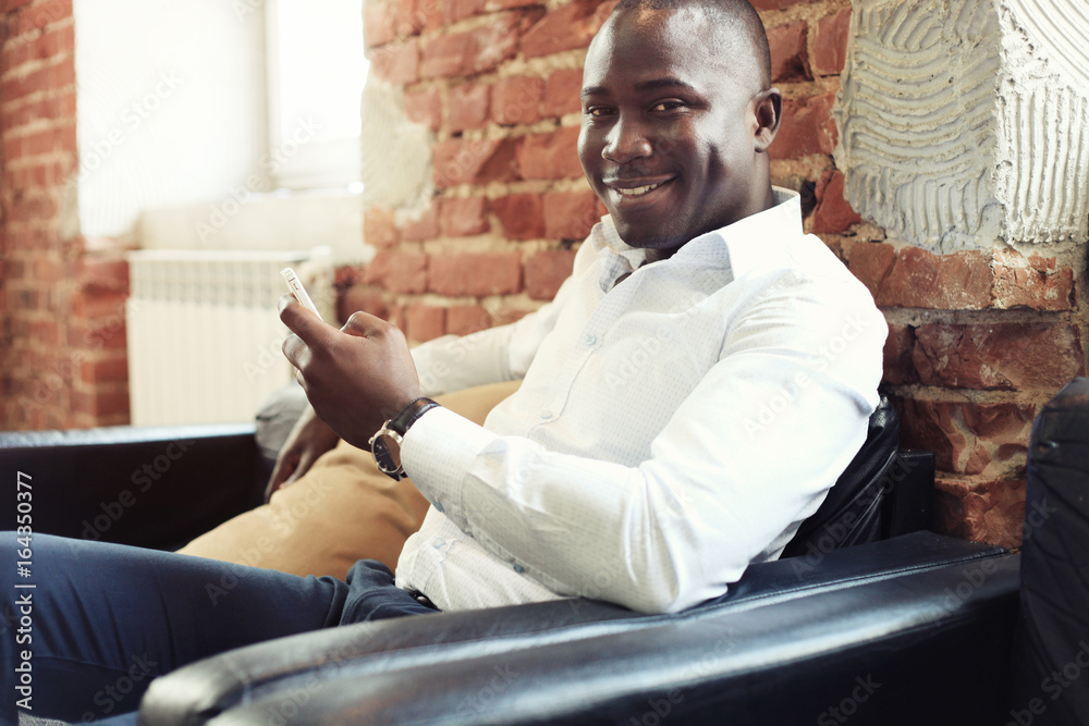 Image of african american professional businessman in business formal attire on his mobile cell smartphone.