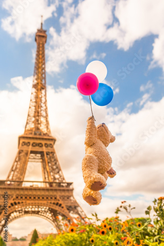 Funny Sky Trip Paris / Cute teddy bear flying with tricolor balloons up to the vintage bright sky in front of Eiffel Tower, Paris, France (copy space) © 75tiks