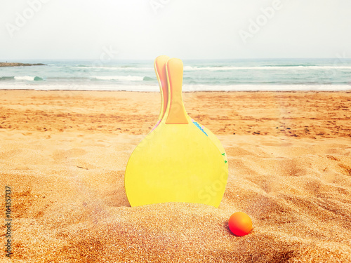 Colorful Rackets and ball on a golden sand in beach
