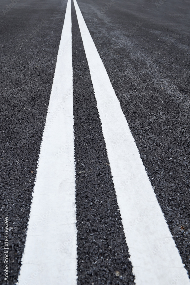 Closeup asphalt road with marking lines for giving directions, traffic lines concept