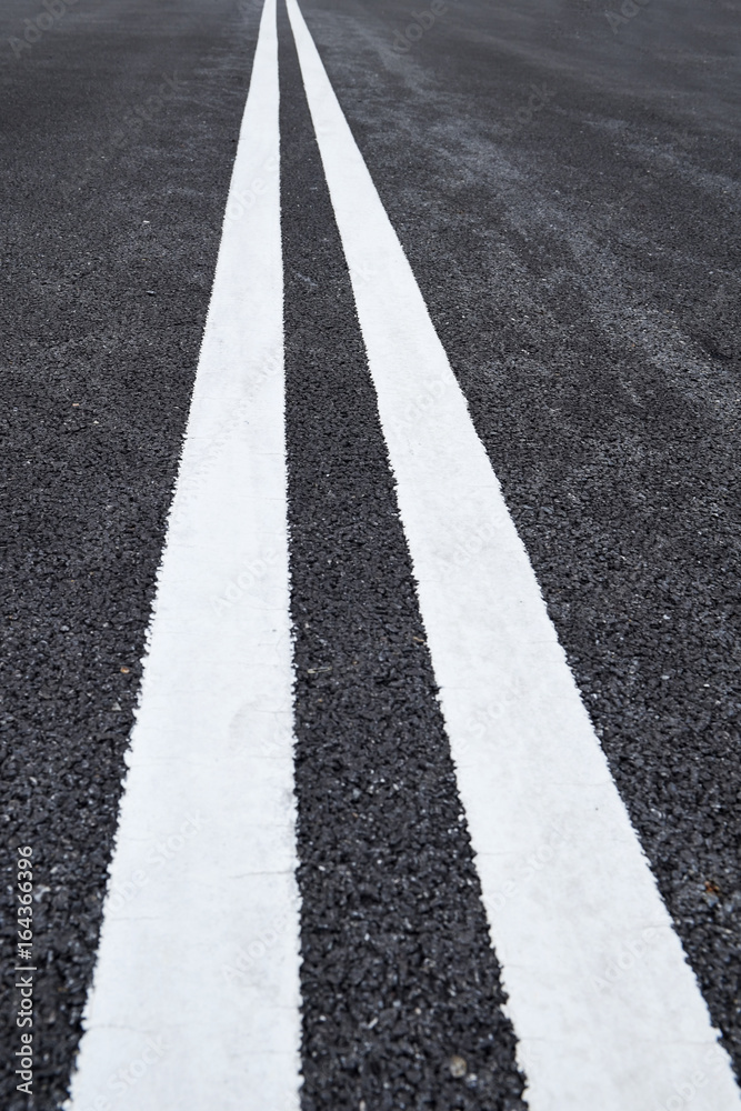 Closeup asphalt road with marking lines for giving directions, traffic lines concept Closeup asphalt road with marking lines for giving directions, traffic lines concept