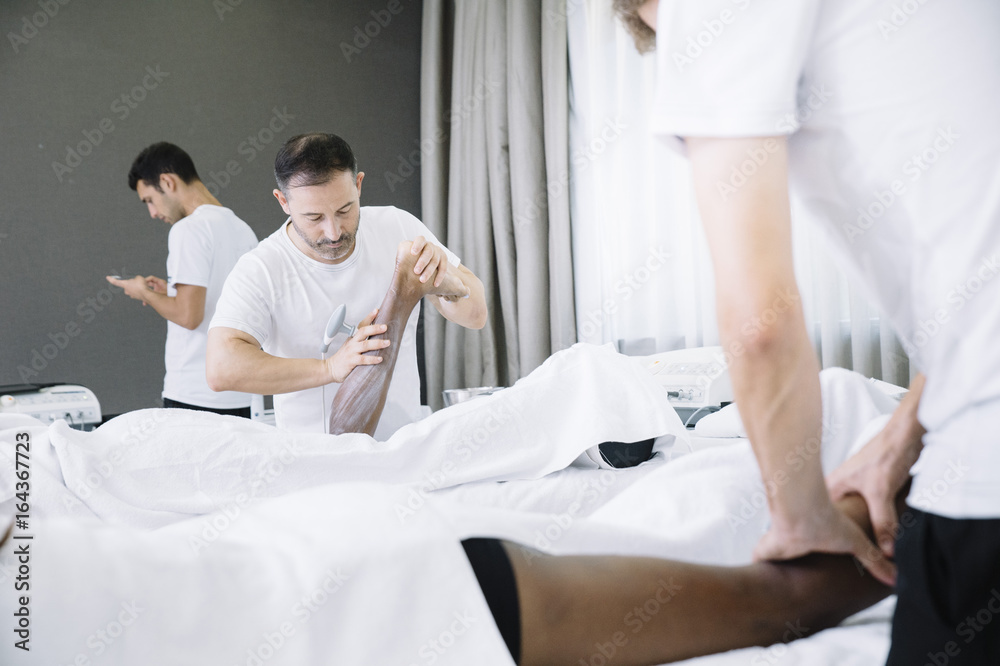 Obraz premium The physiotherapist treating a man using equipment for radio therapy