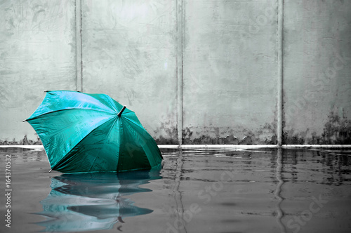 Turquoise umbrella floating concept. Flooded on street. .Waiting for help me after the rain. Black and white colors. Close up.