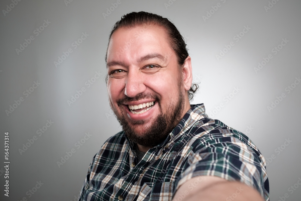 Beautiful young man in casual clothes make selfie on a gray background. He has a happy face, smiling with teeth. Beautiful young man in casual clothes make selfie on a gray background. He has a happy face, smiling with teeth.