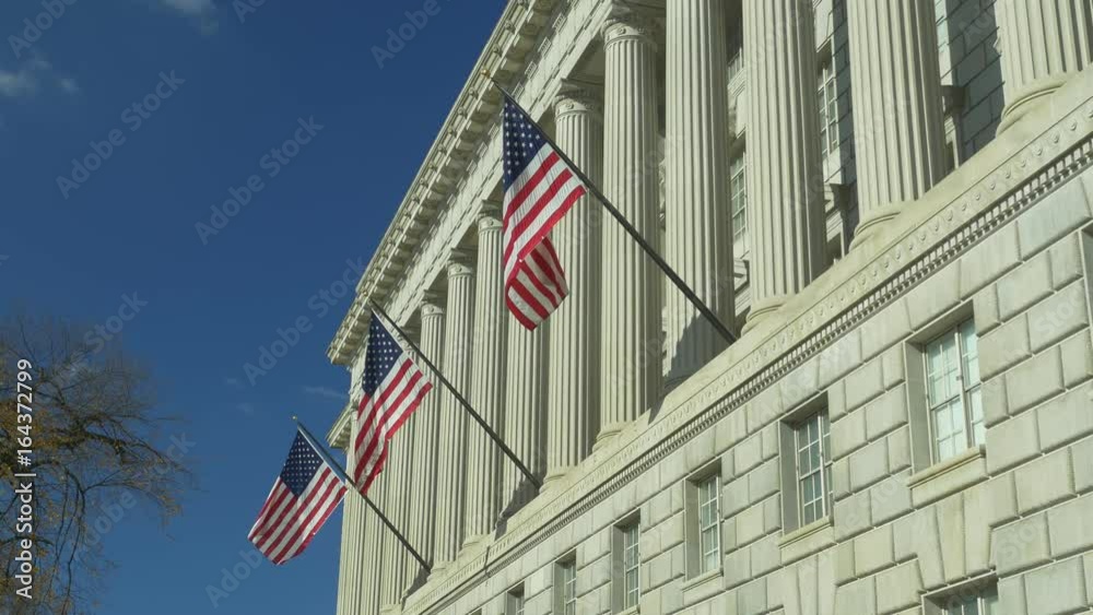 Low angle view of US National Flags on facade of US Department of Commerce in Washington DC