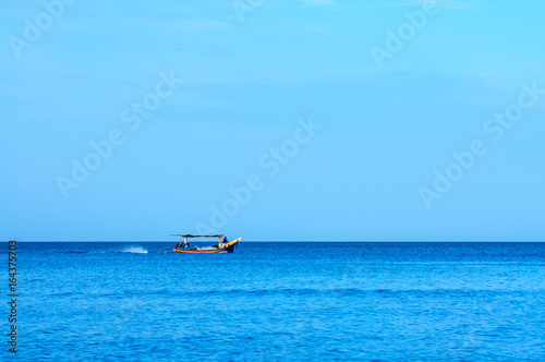 Small tropical fishing boat sailing back from the sea. © HADAPI