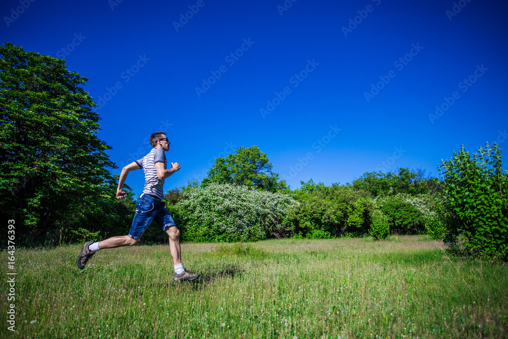 A young man runs along the green grass