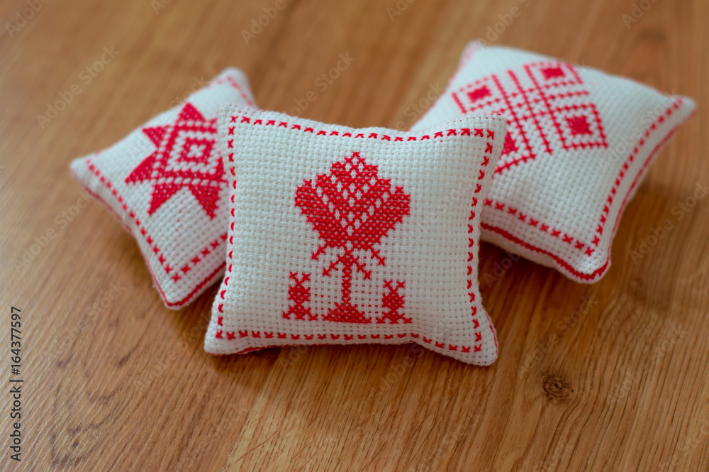 Obraz premium 3 pillows with the national Belarusian ornament symbols, motherhood, life, men, child, family on wooden background