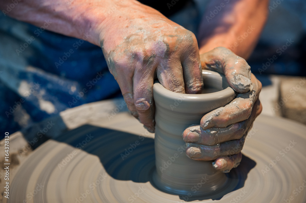 Working gray clay on pottery wheel
