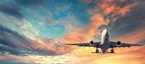 Landing airplane. Landscape with white passenger airplane is flying in the blue sky with multicolored clouds at sunset. Travel background. Passenger airliner. Business trip. Commercial aircraft