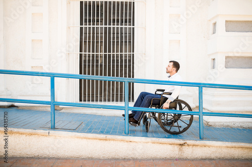 Fotografi Man in wheelchair going up a building access ramp