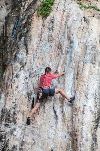 Tourist man climbing on a limestone wall on Krabi province at Thailand.