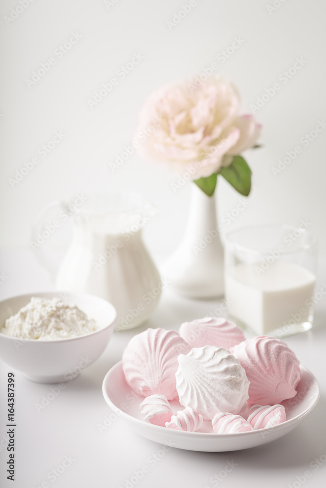 Dairy products in glass, marshmallows white and pink, the flower in the vase. Photography Studio in high key. Plenty of space for text.