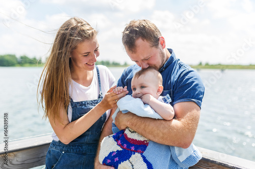 Mother and father with baby son standing on pier by the river © Irina84