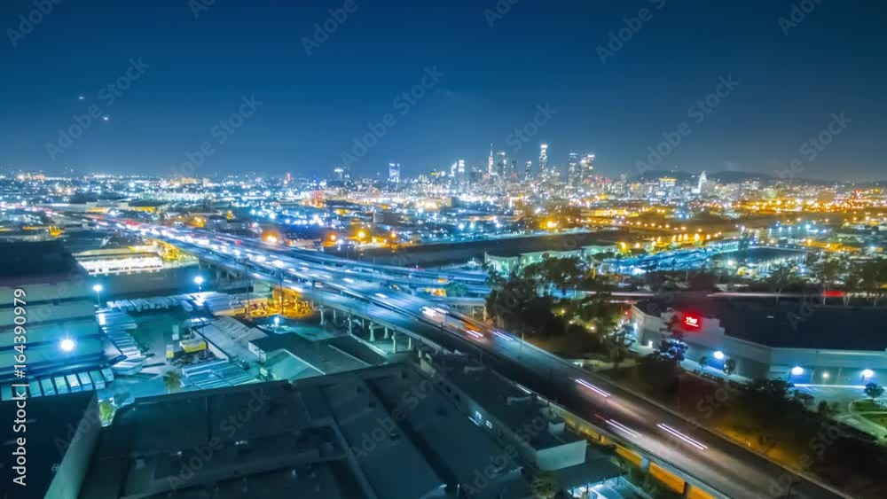 Aerial evening timelapse in motion (hyperlapse) facing downtown Los Angeles after sunset with stunning deep blue sky buildings, and car lights with traffic on a busy street below.