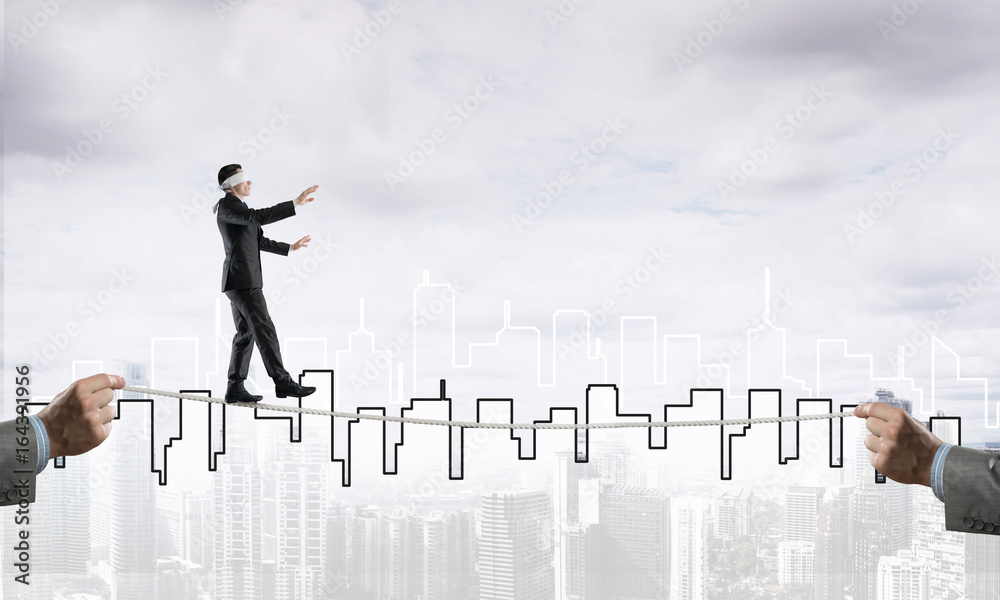 Business concept of risk support and assistance with man balancing on rope Business concept of risk support and assistance with man balancing on rope