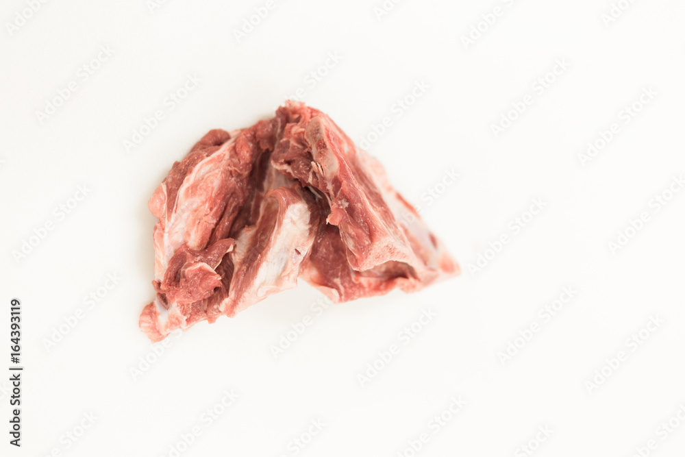 A piece of raw meat against a white cutting board in a butchers shop/ deli market