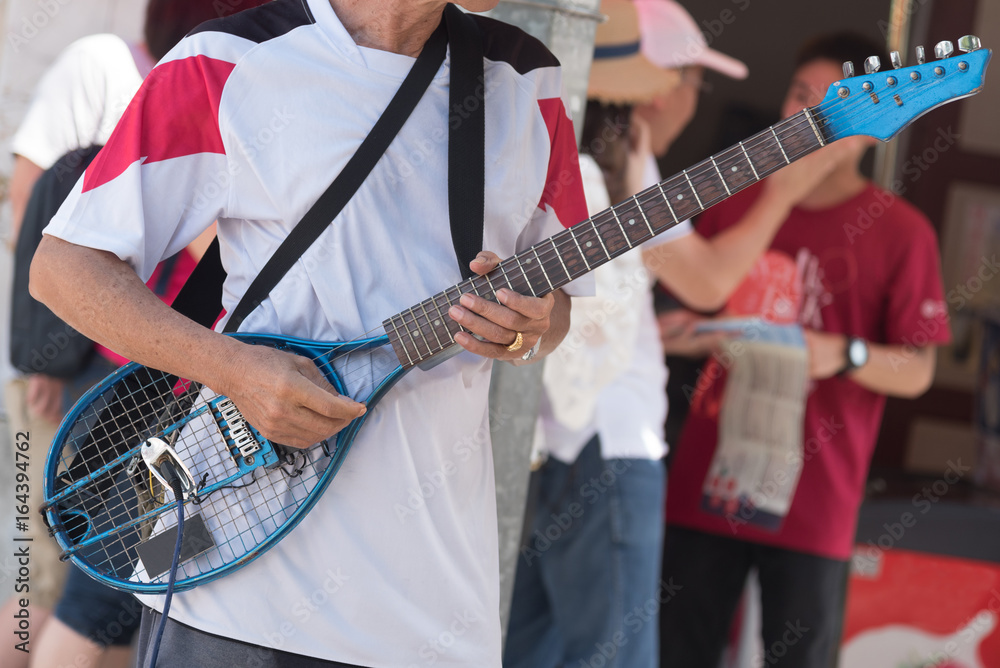 Crop Old Asian man playing guitar made of tennis racket To raise money to  help poor people in public. Stock Photo | Adobe Stock