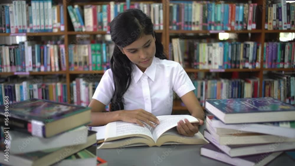 College student reading in the library. She has a willingness to learn. The concept focuses on the love of reading. College student reading in the library. She has a willingness to learn. The concept focuses on the love of reading.