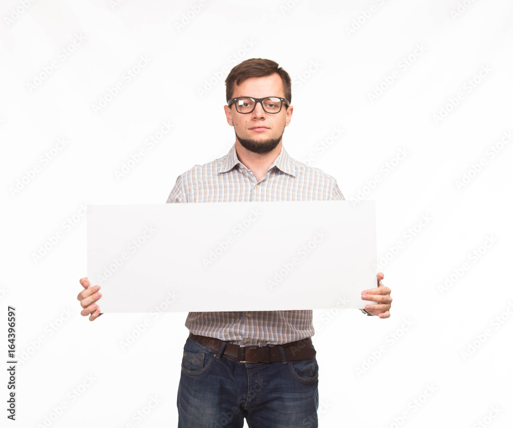Young bored man portrait of a confident businessman showing presentation, pointing paper placard gray background. Ideal for banners, registration forms, presentation, landings, presenting concept.