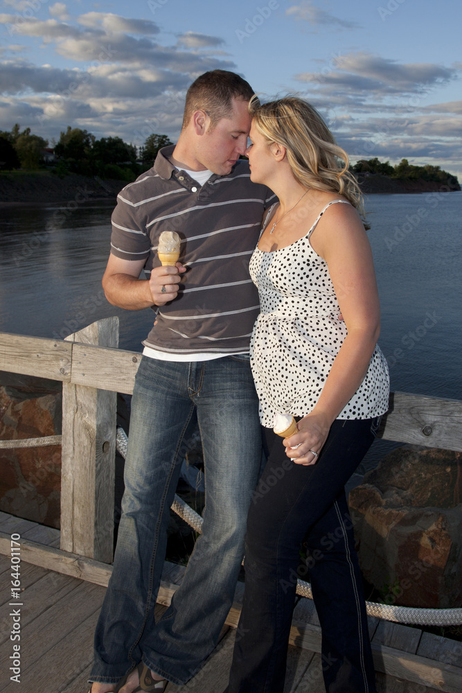 Young in love engaged couple with ice cream on the boardwalk.
