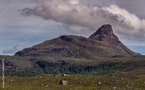 Assynt Peninsula  Scotland - June 7  2012  Brown mountain peak and adjacent hill under heavy brownish skies fronted by green wild rough slopes east of Loch Buine Moire.