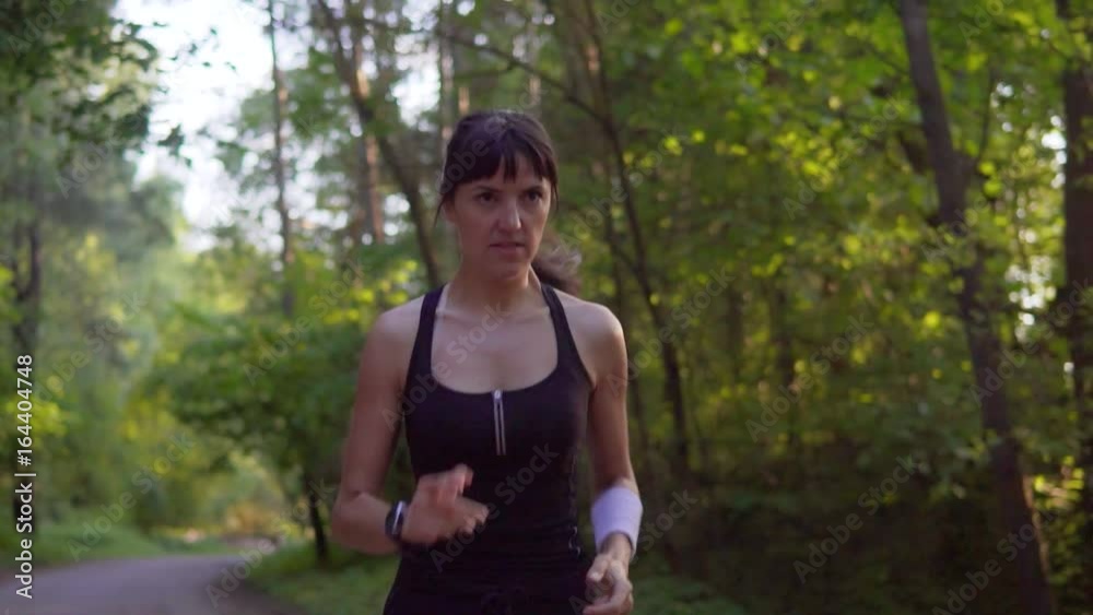 Young woman runner is running down the road in a sporty uniform Young woman runner is running down the road in a sporty uniform