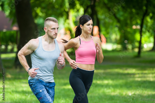 Fototapeta Naklejka Na Ścianę i Meble -  sport woman and man running together in a park in summer