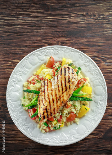 Fototapeta Naklejka Na Ścianę i Meble -  couscous salad with grilled chicken and asparagus on white plate. wooden rustic table. healthy food