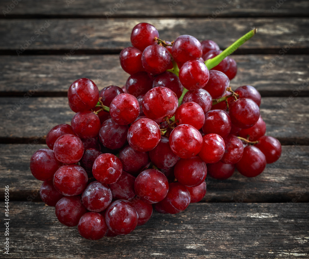 Ripe red grape. Pink bunch in a old rustic wooden table Ripe red grape. Pink bunch in a old rustic wooden table